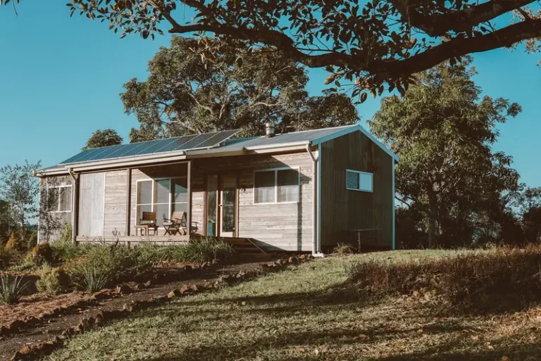 A charming wooden house in Australia featuring solar panels, surrounded by lush greenery. Stock Photo