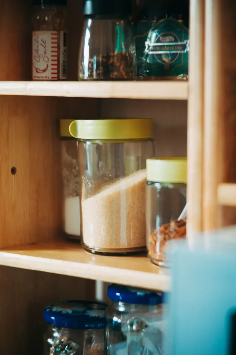 Neatly arranged kitchen pantry with glass jars and ingredients on wooden shelves. Stock Photo