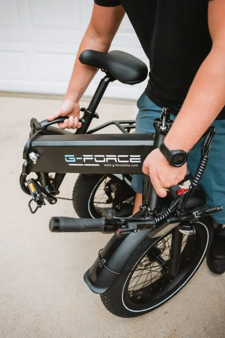 Person folding a G-Force electric bike, showcasing portability and design. Stock Photo