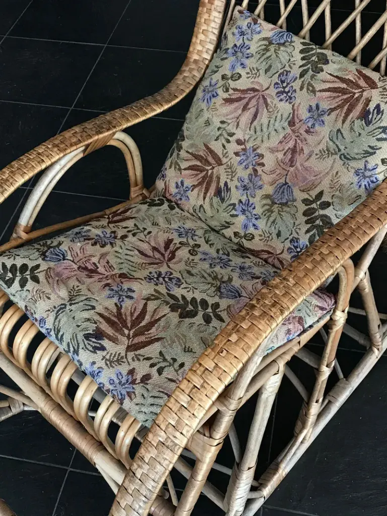 Elegant wicker armchair featuring floral patterned cushions, ideal for stylish interiors. Stock Photo