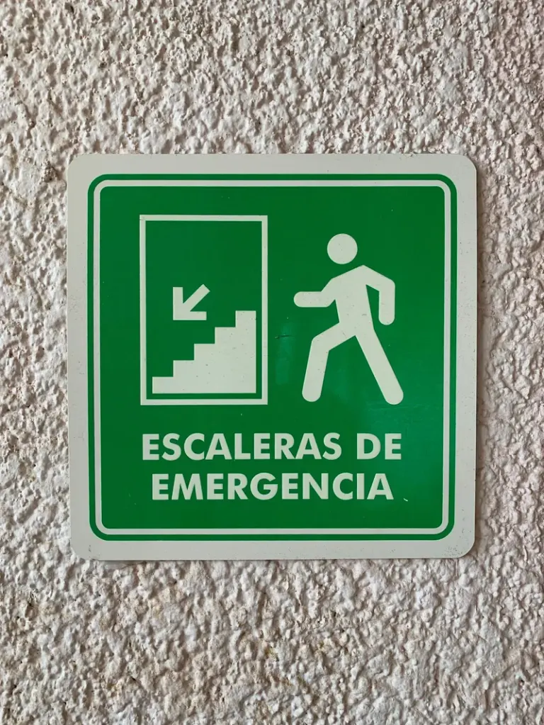 Close-up of a green emergency stair sign on a wall, featuring Spanish text. Stock Photo