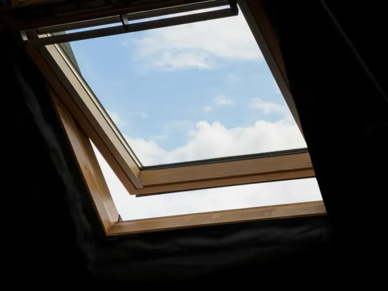 Low angle view of an open skylight with blue sky and white clouds visible. Stock Photo