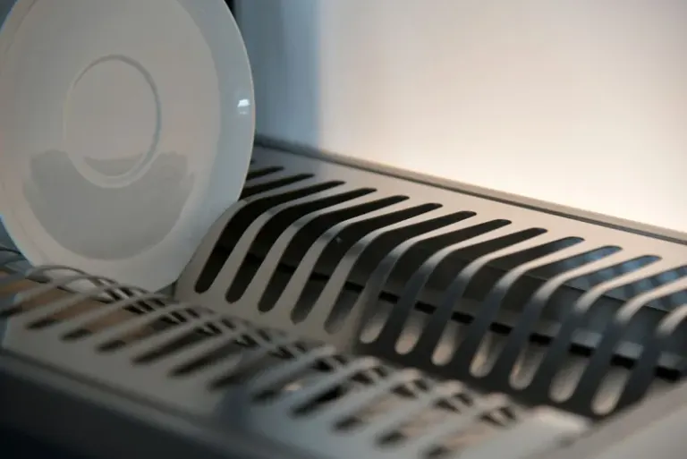Elegant ceramic plate on a sleek metal dish rack in a modern kitchen setting. Stock Photo