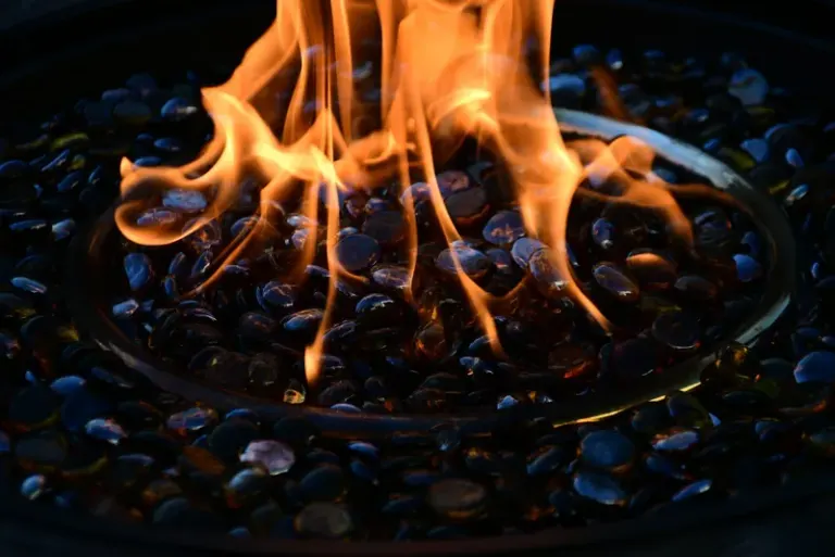 Close-up view of mesmerizing fire flames dancing over decorative glass stones in a fire pit. Stock Photo