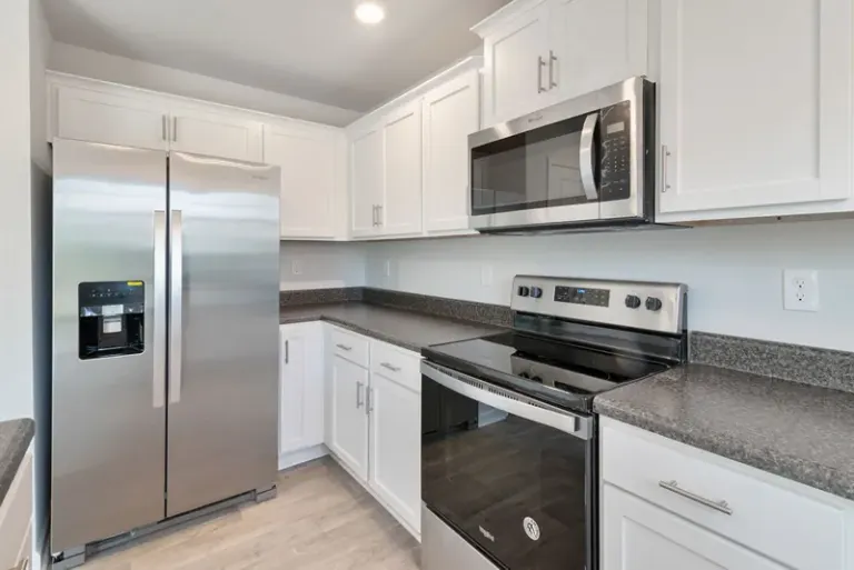 Sleek kitchen with stainless steel appliances and white cabinetry. Stock Photo