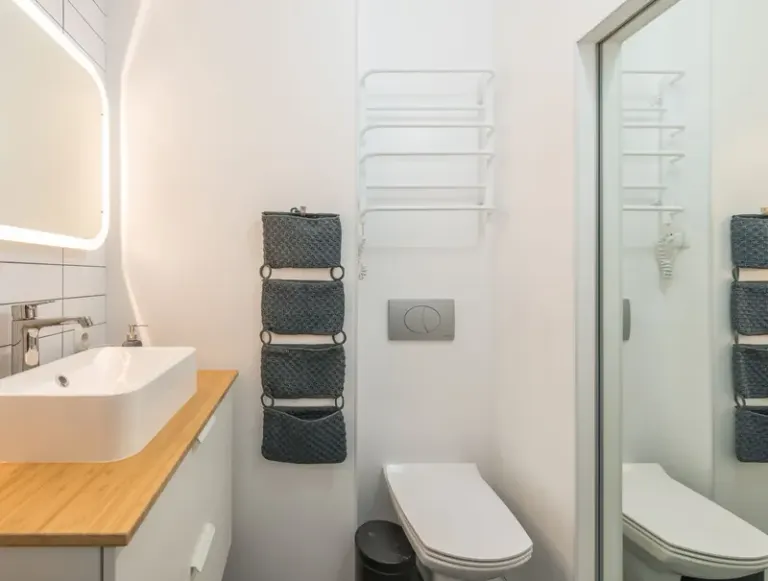 Small modern bathroom with ceramic toilet bowl and sink under illuminated mirror in modern apartment Stock Photo