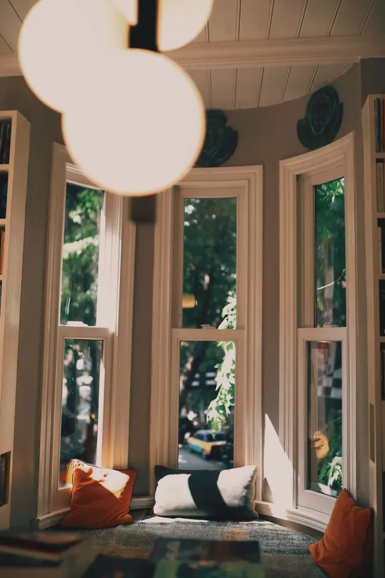Inviting bay window seat with pillows and warm lighting, creating a peaceful reading nook. Stock Photo