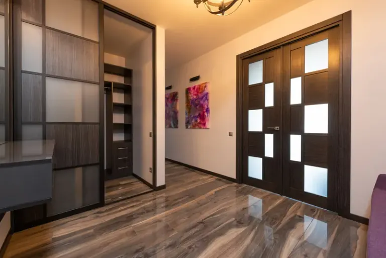 Contemporary room interior with closet on floor reflecting door against paintings on wall in light house Stock Photo