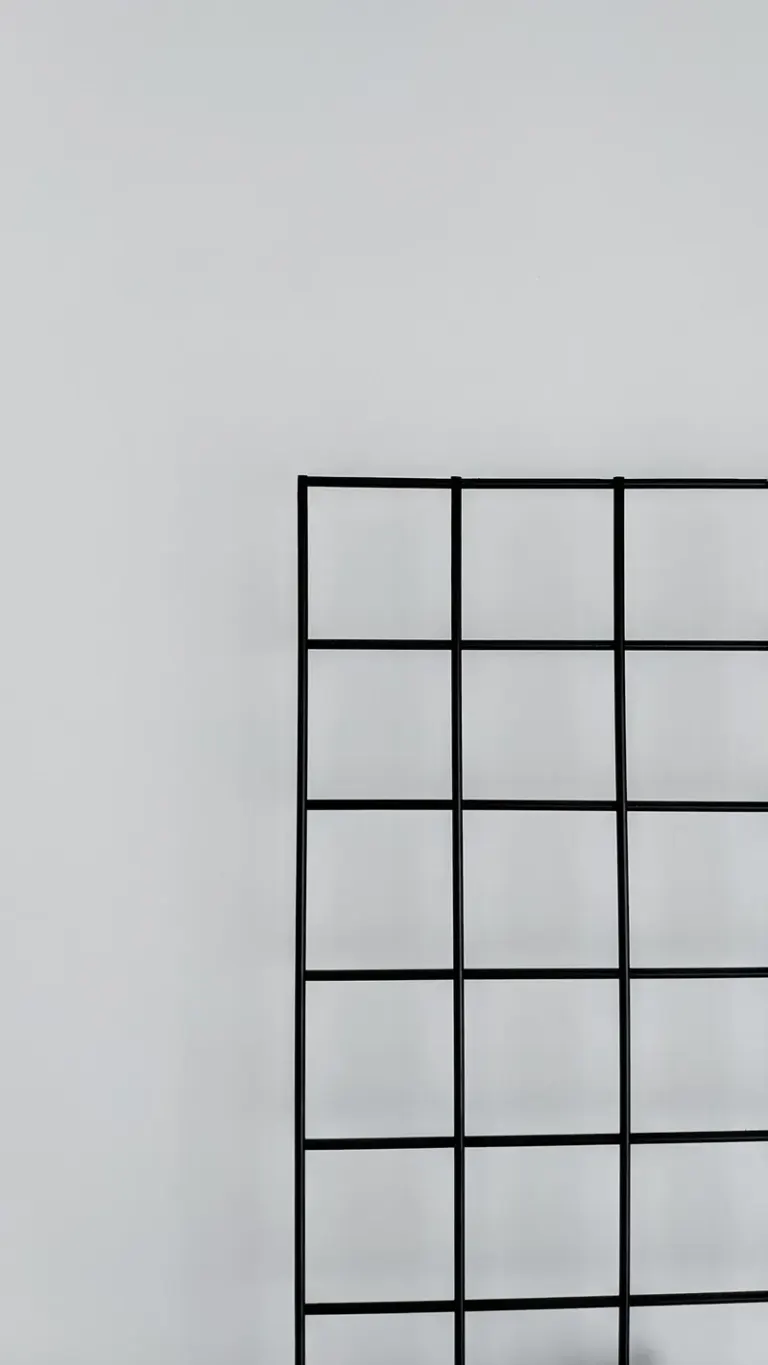 A minimalist black metal grid displayed against a light gray wall, showcasing simplicity and modern design. Stock Photo