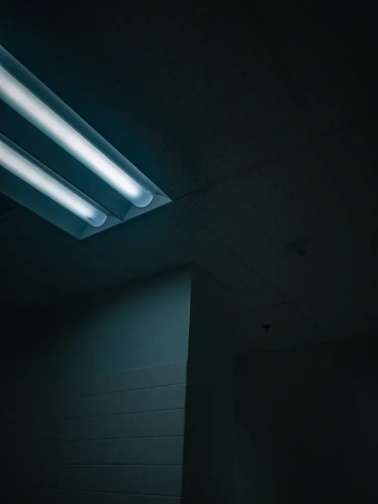 Moody interior capture of ceiling with fluorescent light, casting a soft glow. Stock Photo