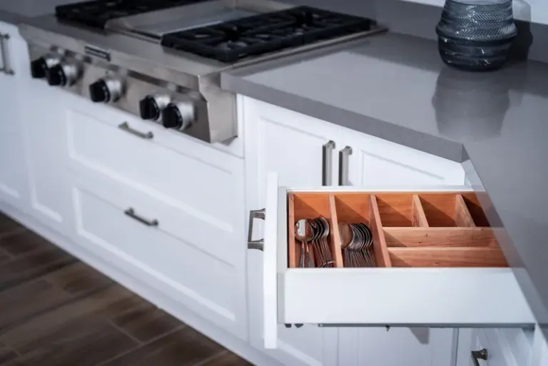 Sleek modern kitchen showcasing a neatly organized drawer next to a stainless steel stove. Stock Photo