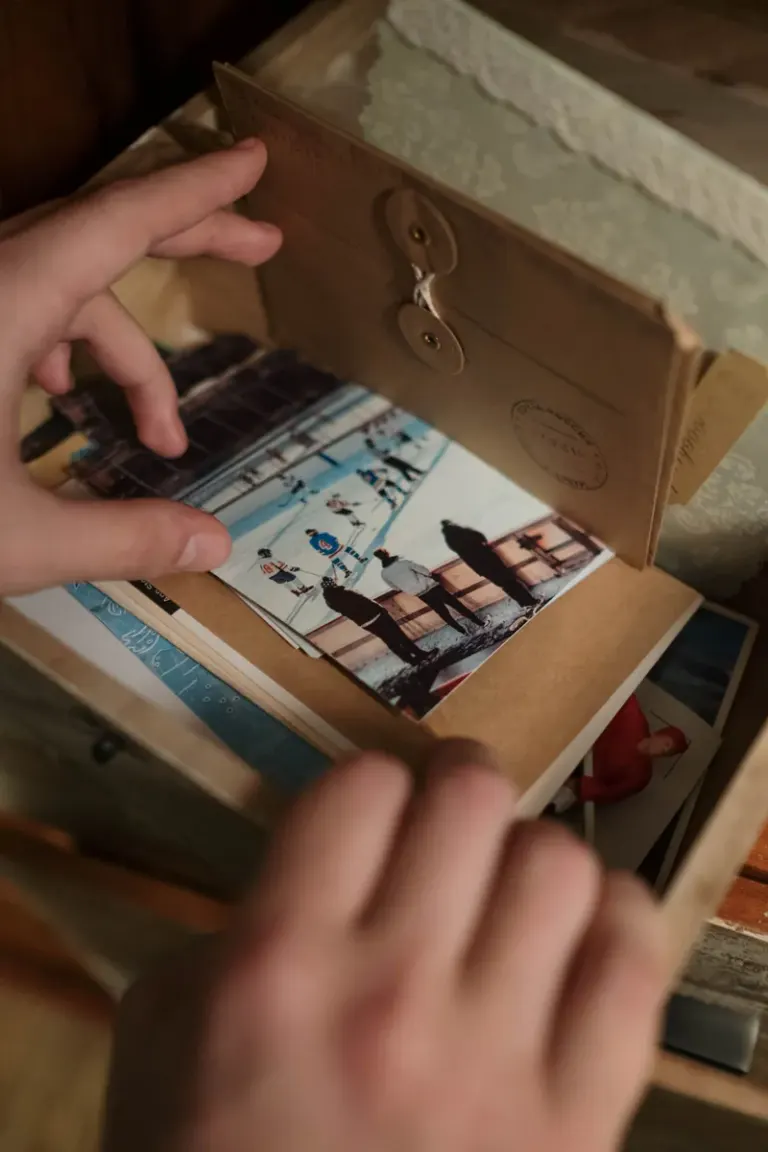 A close-up of hands sorting vintage photos in a drawer, evoking nostalgia. Stock Photo