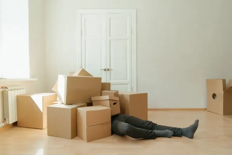 Person on floor surrounded by cardboard boxes during moving; concept of stress and relocation. Stock Photo