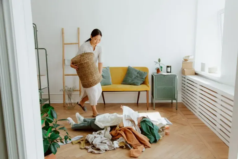 A woman organizing clothes in a cozy living room, creating a tidy and welcoming atmosphere. Stock Photo