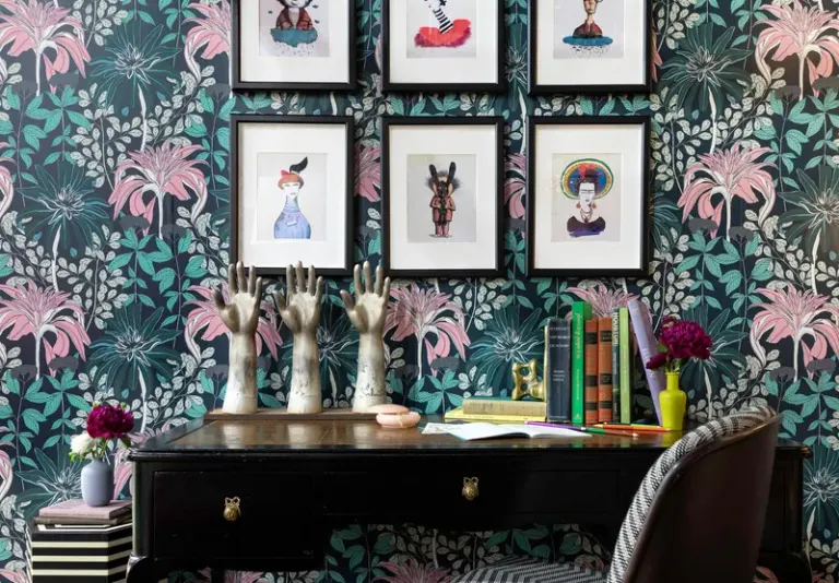 A creative desk setup with floral wallpaper, framed art, and decorative objects. Stock Photo