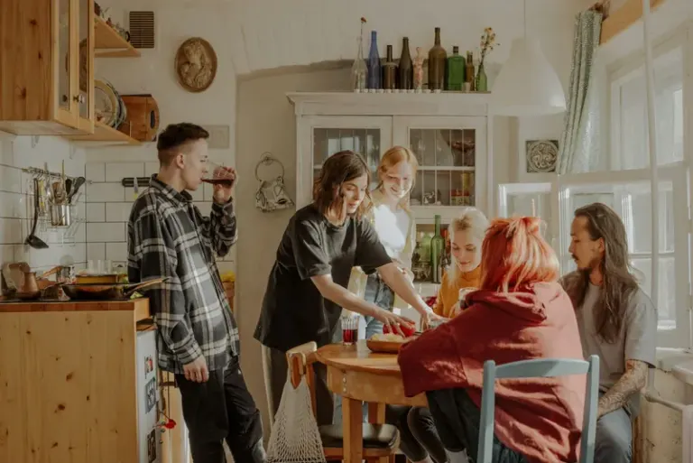 Friends enjoy a relaxed moment together in a sunny kitchen, reflecting a lifestyle of camaraderie and warmth. Stock Photo