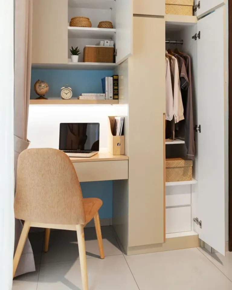 Bright and organized workspace featuring a desk, chair, and open wardrobe for storage. Stock Photo