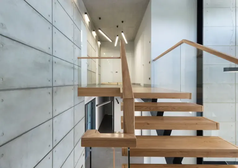 Fragment of interior design of contemporary loft style house with wooden steps with glass fence leading to second floor Stock Photo