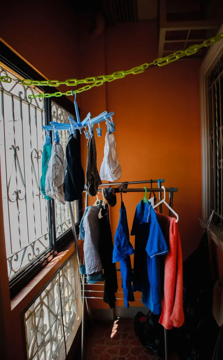 Clothes drying indoors on a rack with sunlight through windows. Stock Photo