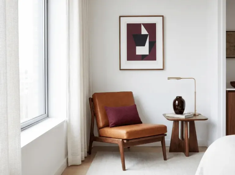 A characterful apartment corner with a leather chair, art, and side table